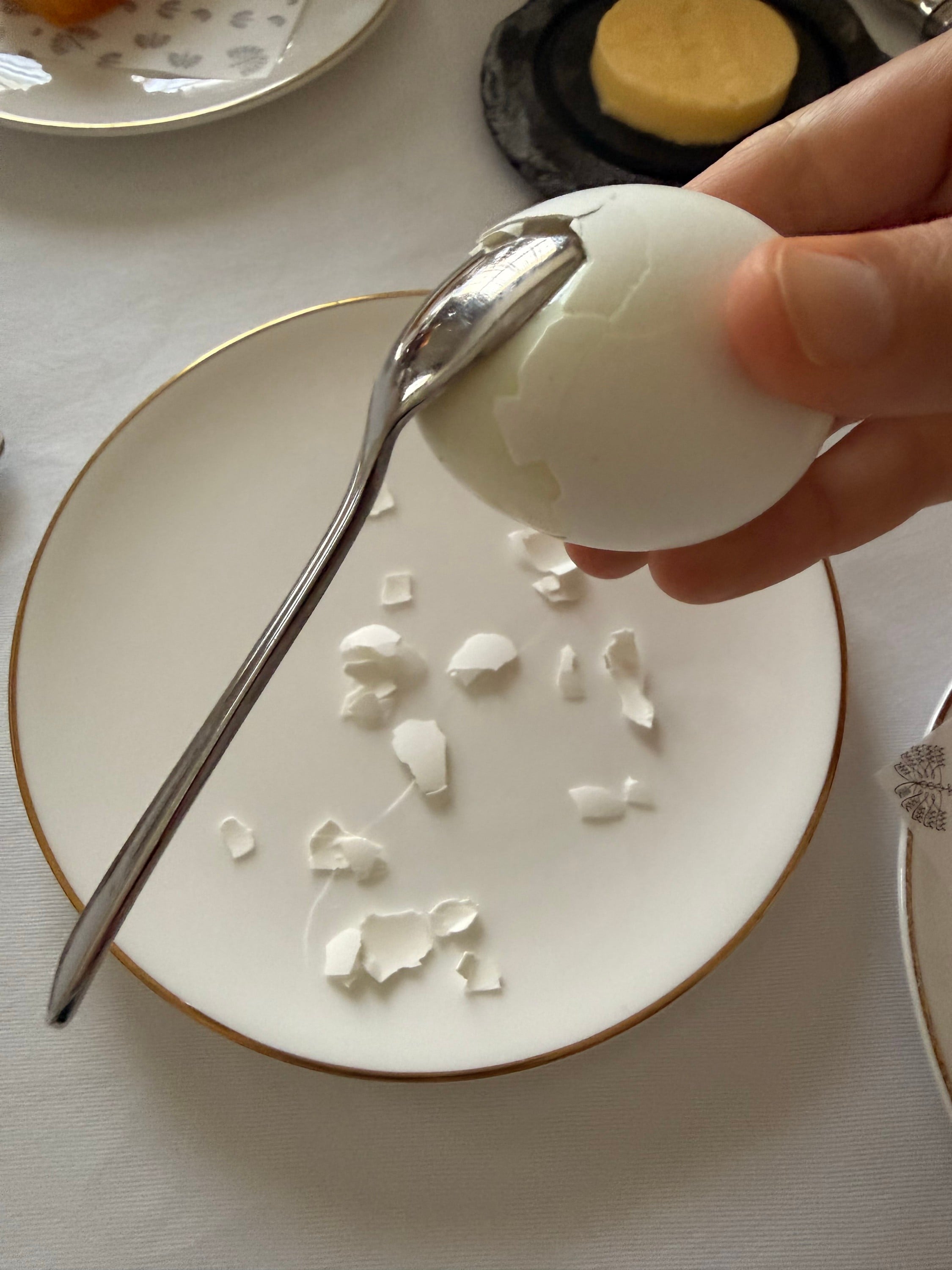 Using a spoon to peel the eggshell