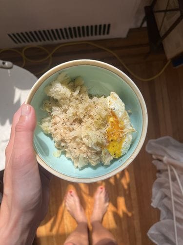 Oatmeal topped with sauerkraut , a fried egg, and drizzle of sesame oil