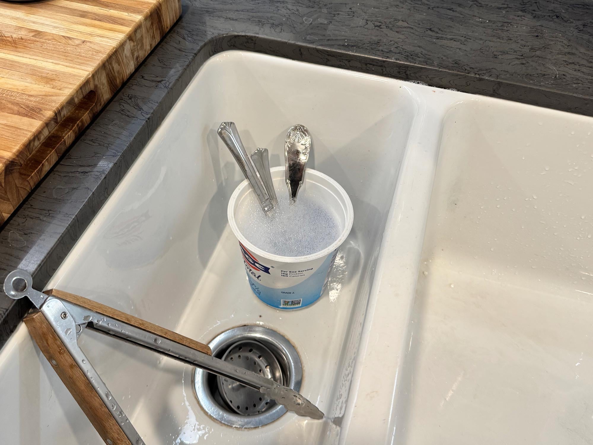 A yogurt container full of soapy water in the sink